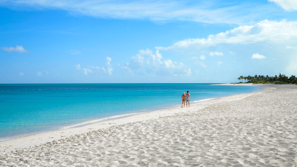 Couple walking on sunny Turks and Caicos beach