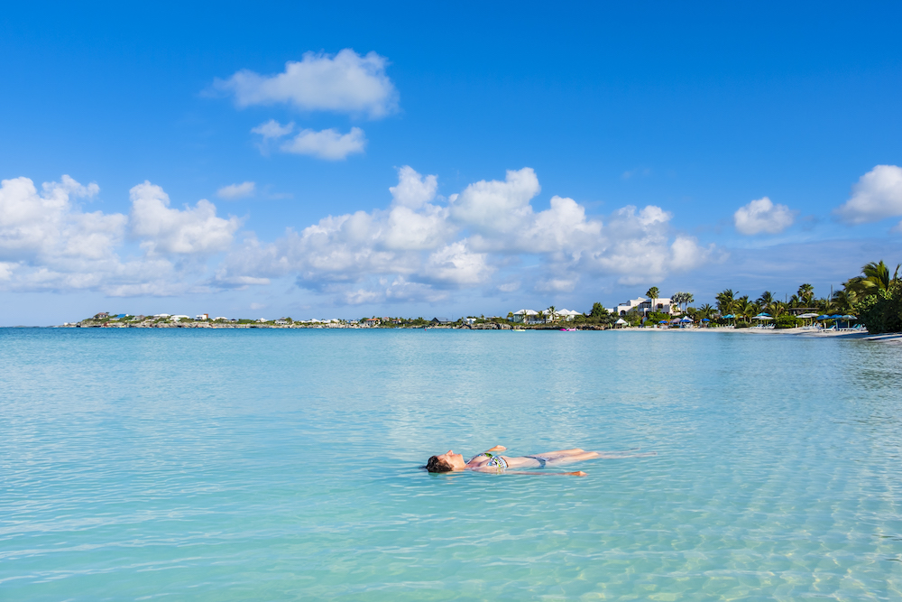 Turks and Caicos, Providenciales - woman floating on clear, turquoise water 