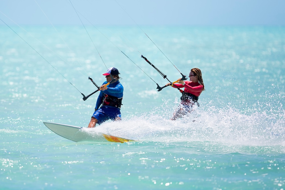 A man and a woman kiteboarding side-by-side in the ocean
